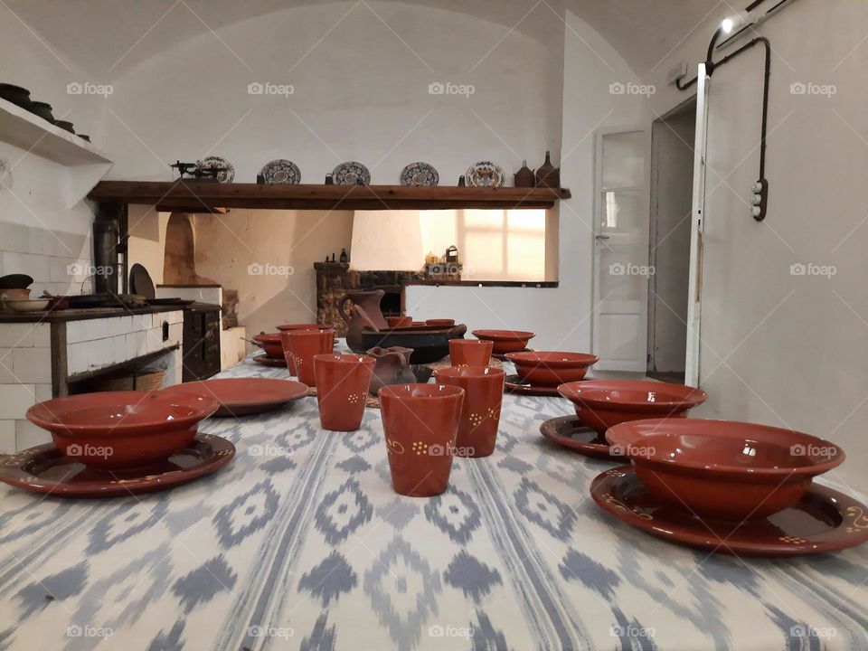 Handycraft table service. Ceramic tableware set on a Majorcan traditional tablecloth of "llengües" or ikat. Inside an ancient rural kitchen. Calvia, Majorca, Spain.