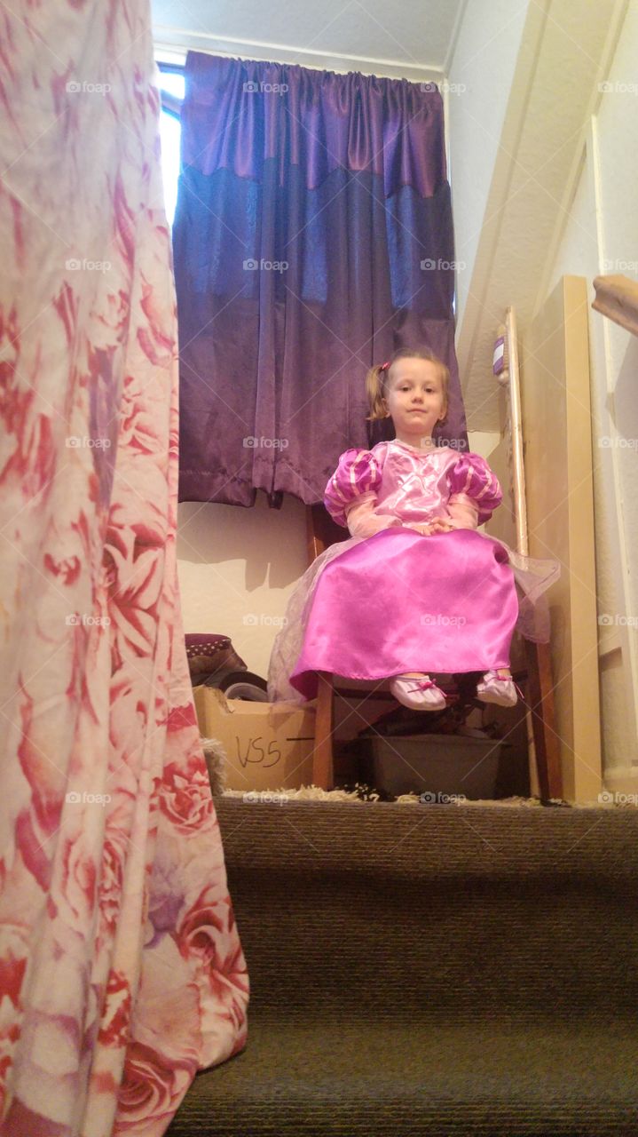 View of young girl in dress sitting on a chair