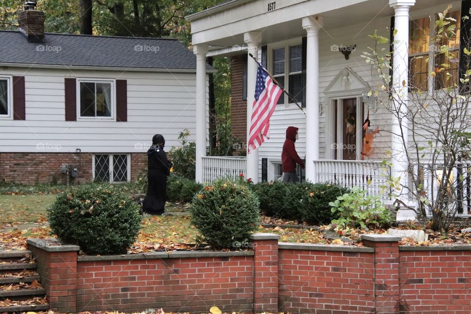 Kids trick or treating at hone with American Flag