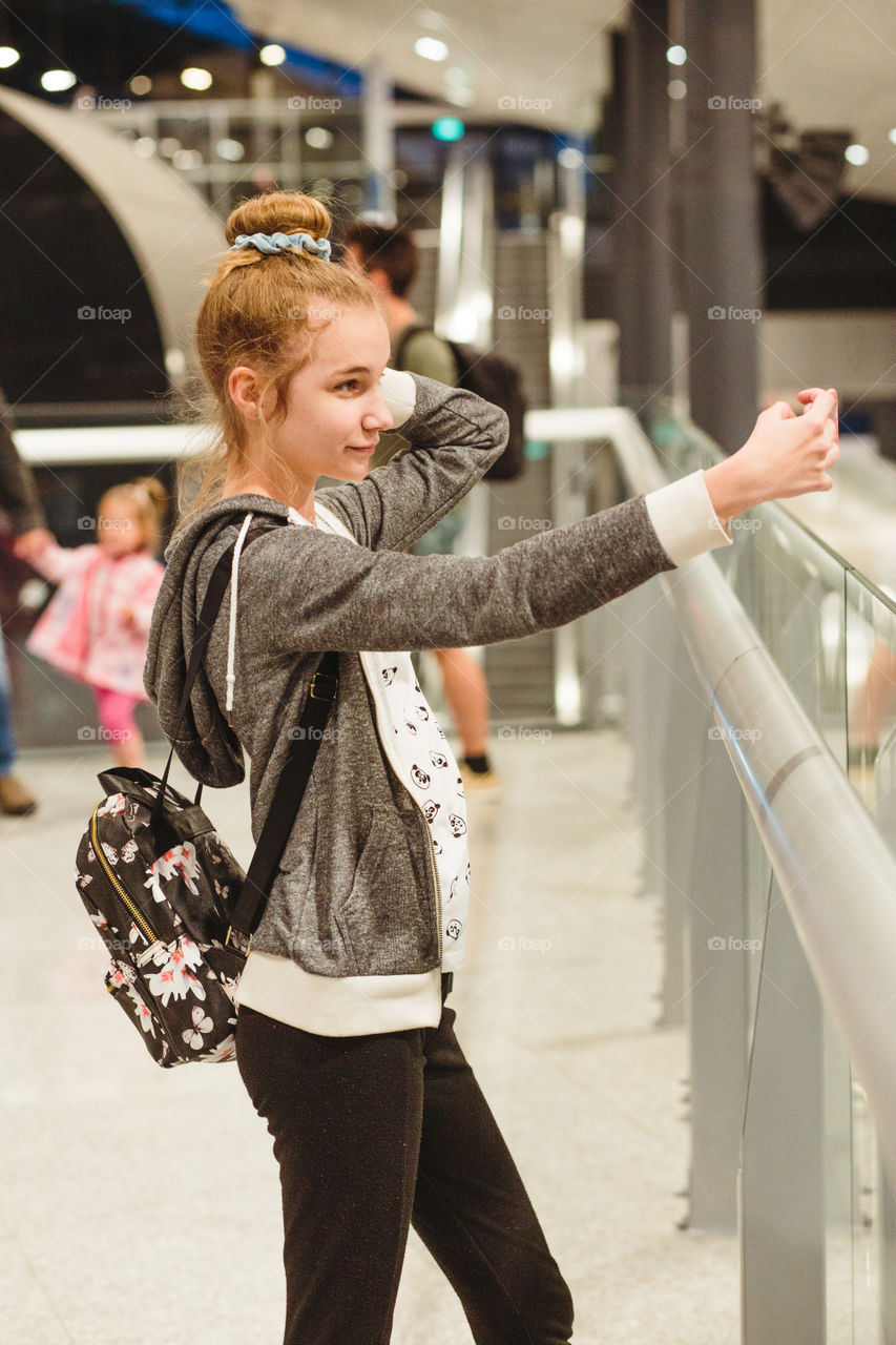 Young woman taking selfie using smartphone standing in railway station