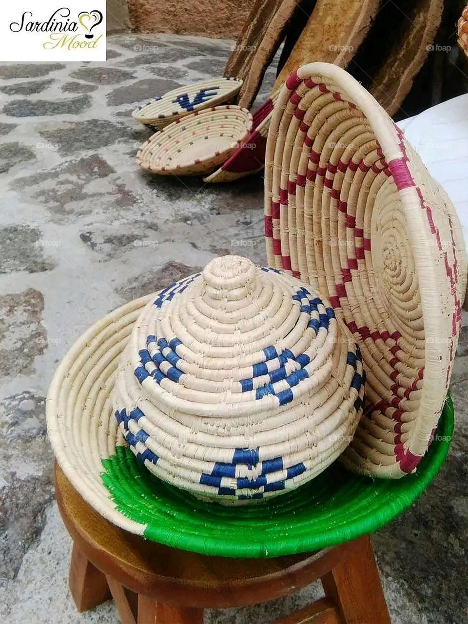 The image shows a group of hand -made dishes of wicker, decorated with colored embroideries with beautiful floral shapes, and is elegantly displayed in a warm corner that combines heritage and beauty, which gives the place an artistic spirit and attr