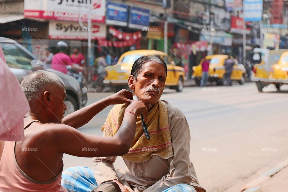 Indian man getting shaved . Indian man getting a shave on the curb on the streets in Kolkata