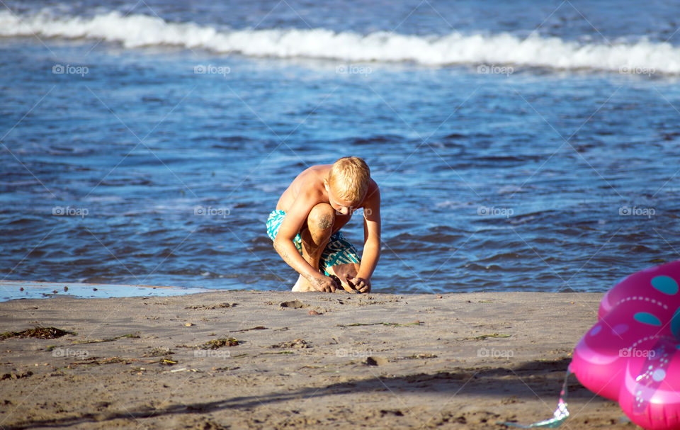 Cute little boy playing with the sand at the beach