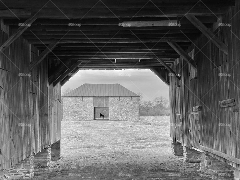 Two barns on a farm with a family standing in the one further away