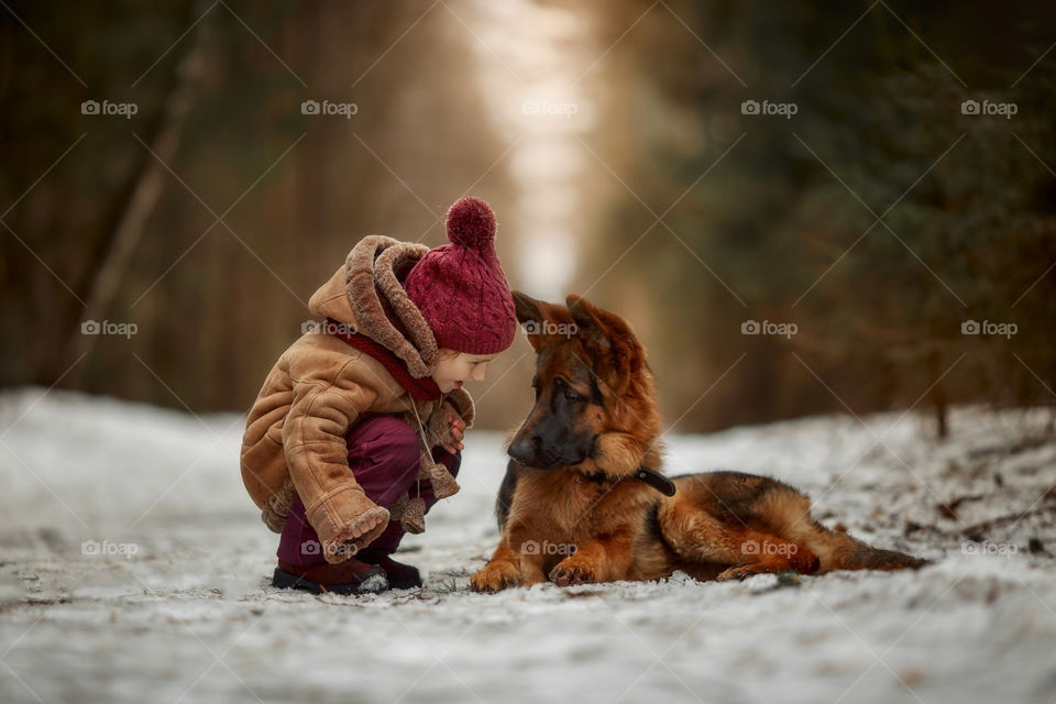 Little girl with German shepherd 6-th months puppy at early spring forest