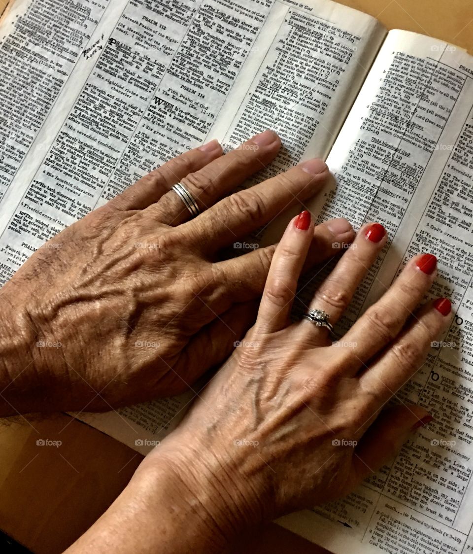 Hands of husband and wife on a Bible