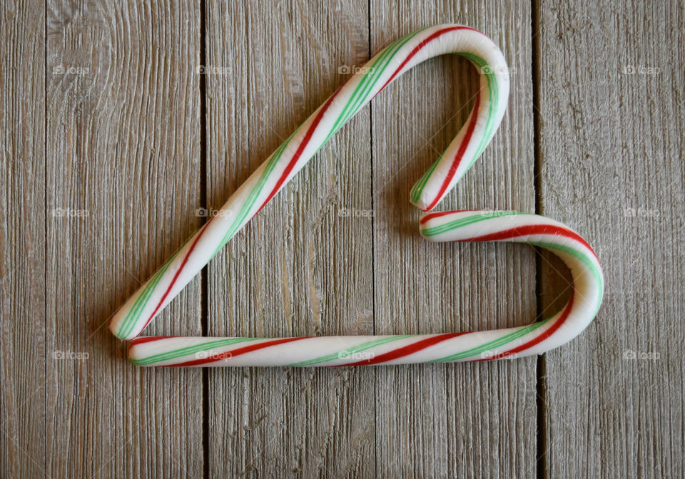 Candy cane in shape of a heart on wood background