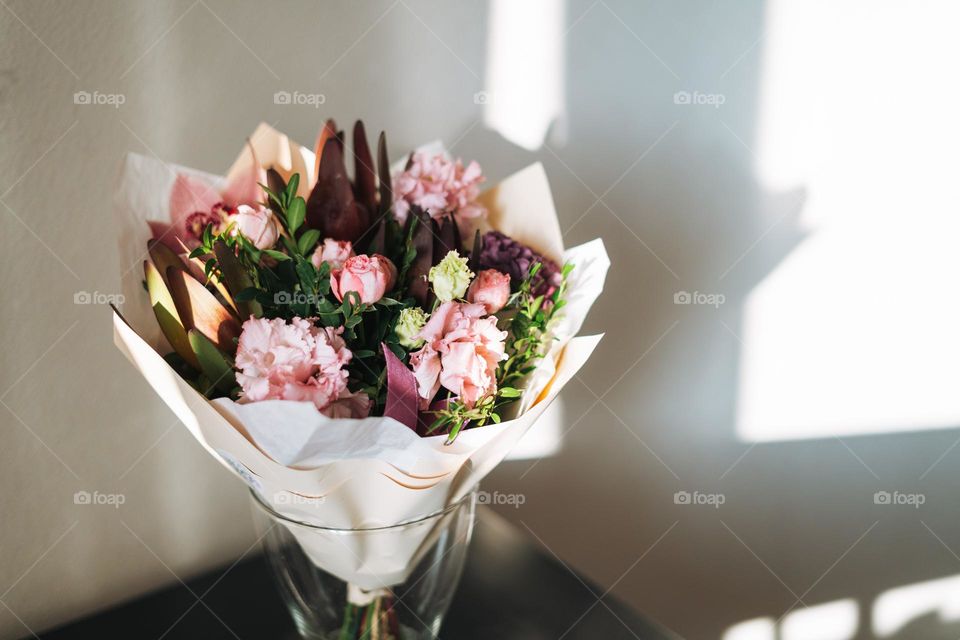Bouquet of different flowers in vase on table at home 