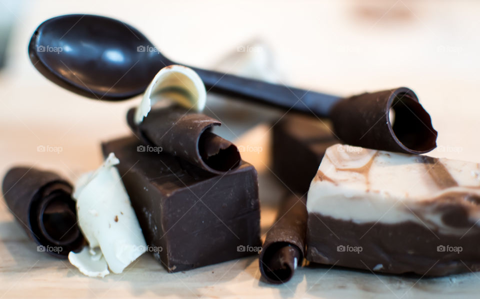 Pieces of fudge and blocks of chocolate in pieces with dark chocolate shavings and spoon made of chocolate, artisanal chocolate arts gourmet confections photography