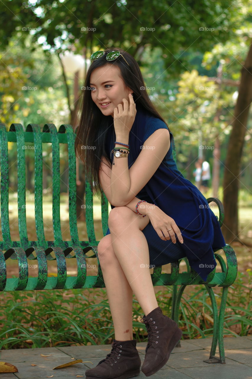Smiling asian woman sitting on bench