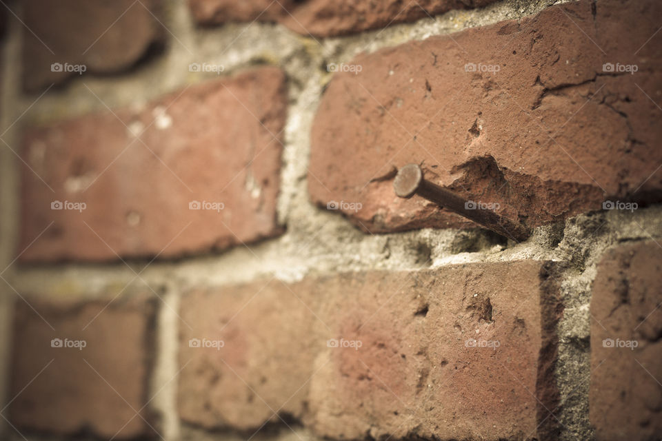 rusty nail in brick wall