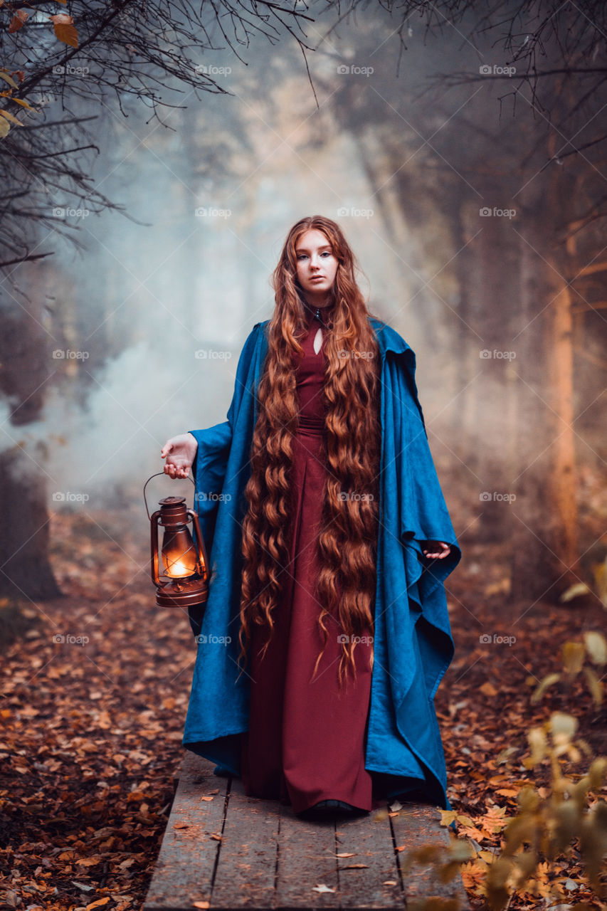 Young woman with long red hair in blue coat. Fantasy photography