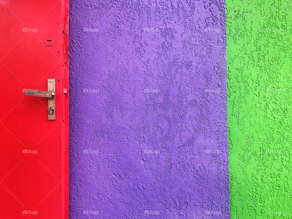 Red door in front of colorful wall 