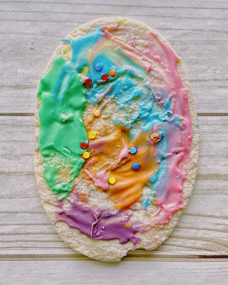 Making a large Easter egg cookie with a toddler, baking with children, frosting sugar cookies with toddlers, colorful sugar cookies for Easter, Easter tradition of baked by sugar cookies, baking homemade cookies 
