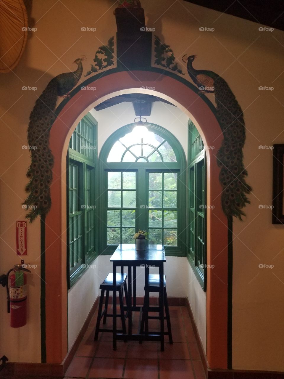 Green window frame in an adobe Spanish-style cottage, with wall paintings.