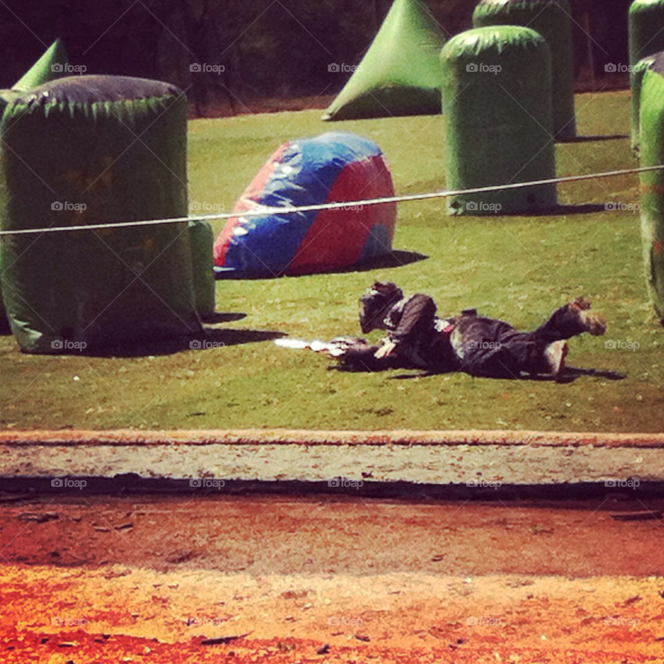 Paintball player sliding into a bunker