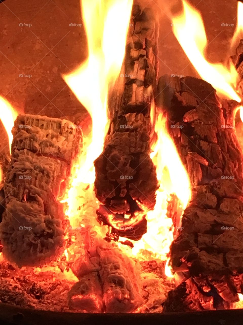 Close up view of wooden logs burning in the flames on a fire in a chiminea in the garden
