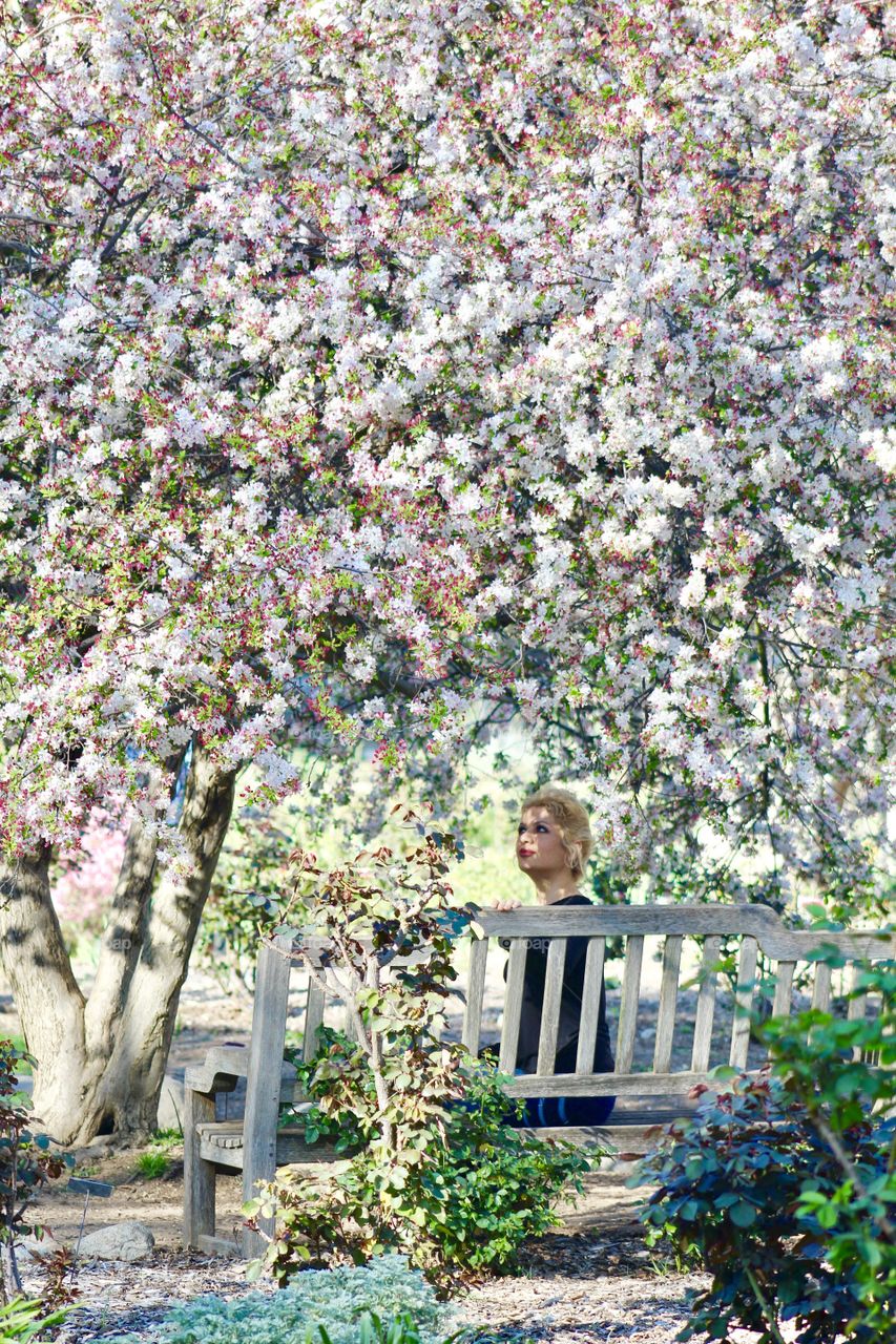 Beautiful woman sitting on bench in garden