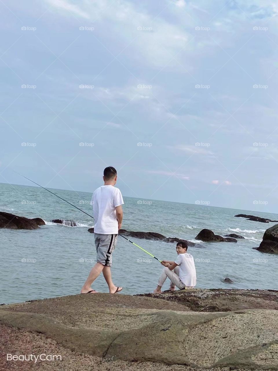 Two handsome men fishing at the seaside