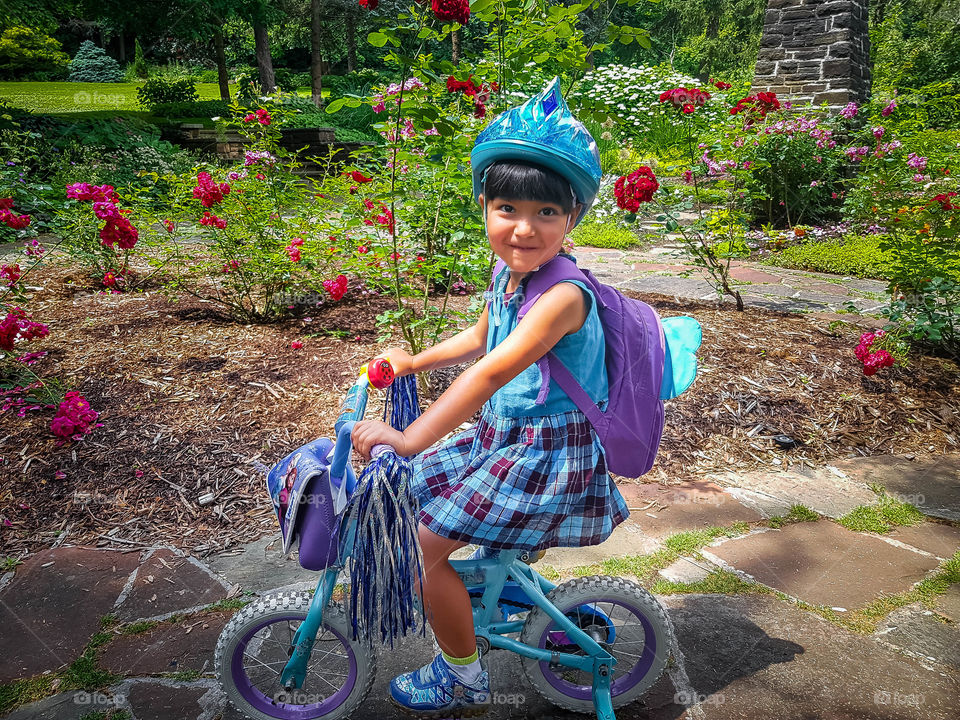 Happy little girl in a helmet riding a bike