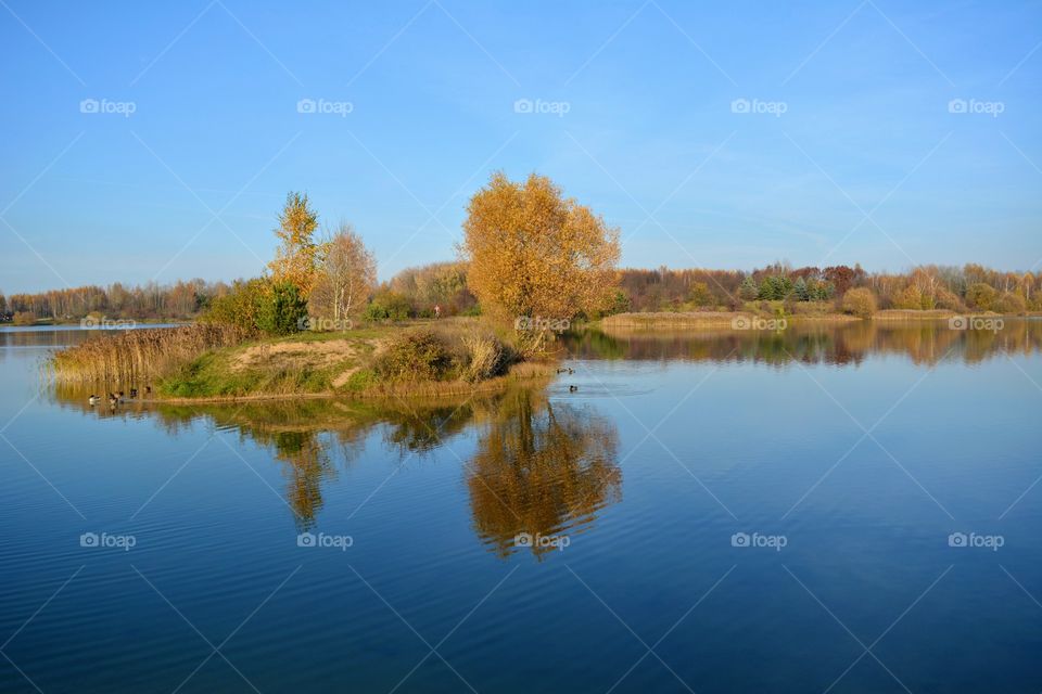 beautiful autumn landscape lake and person walking blue sky background, and reflection