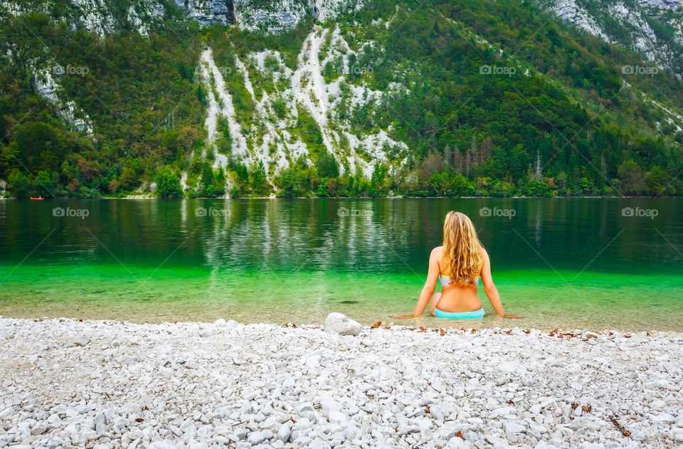 Woman sitting at lake Bohinj, Slovenia