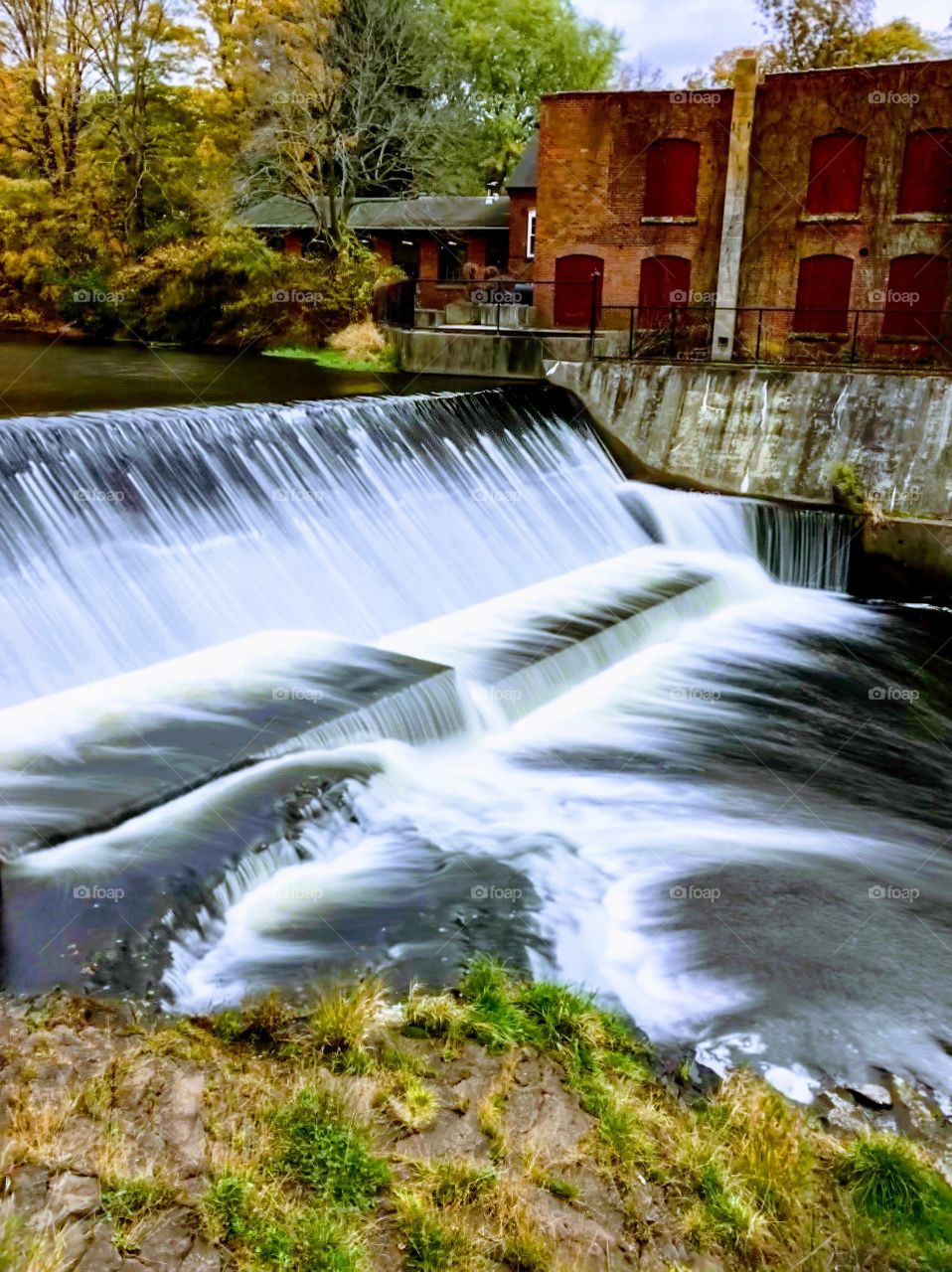 Waterfall next to an old mill on a lake
