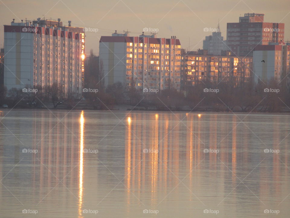 reflection of the sun's rays in the windows of houses and on the ice of the reservoir