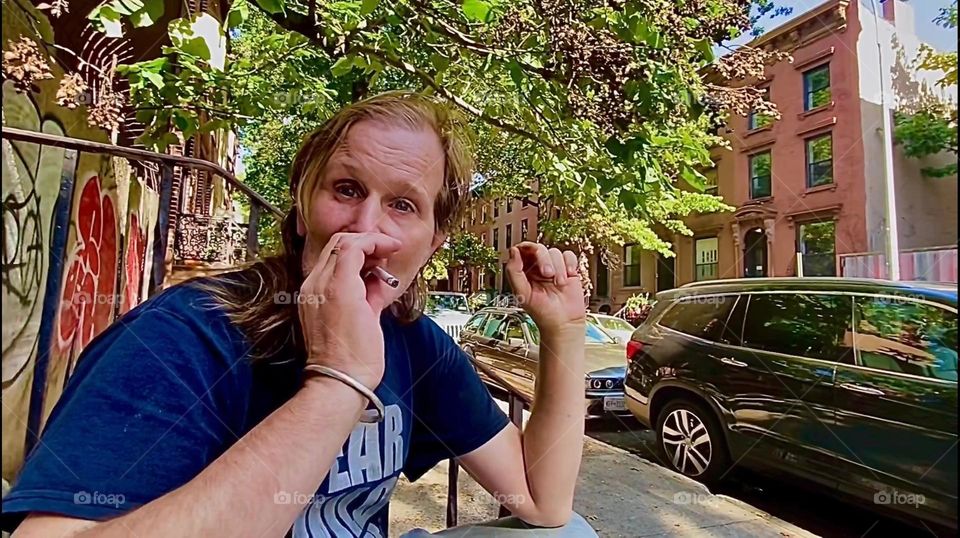 “Timothy Trespas”, my significant other and longtime partner in life is taking a drag off his cigarette sitting on our favorite stoop on “Waverly St” off “Fulton St” in “Clinton Hill”, Brooklyn, NY. 2022. Hypnotic Productions