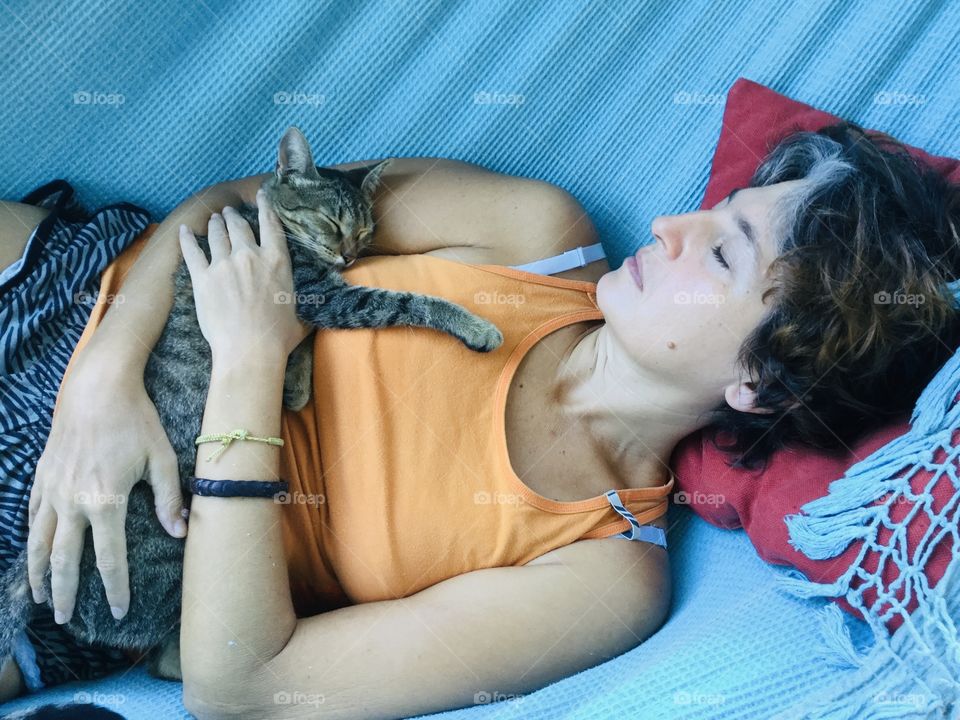 Woman sleeping with cat on hammock 