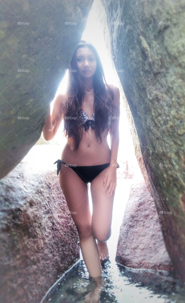 Woman in bikini standing between rocks