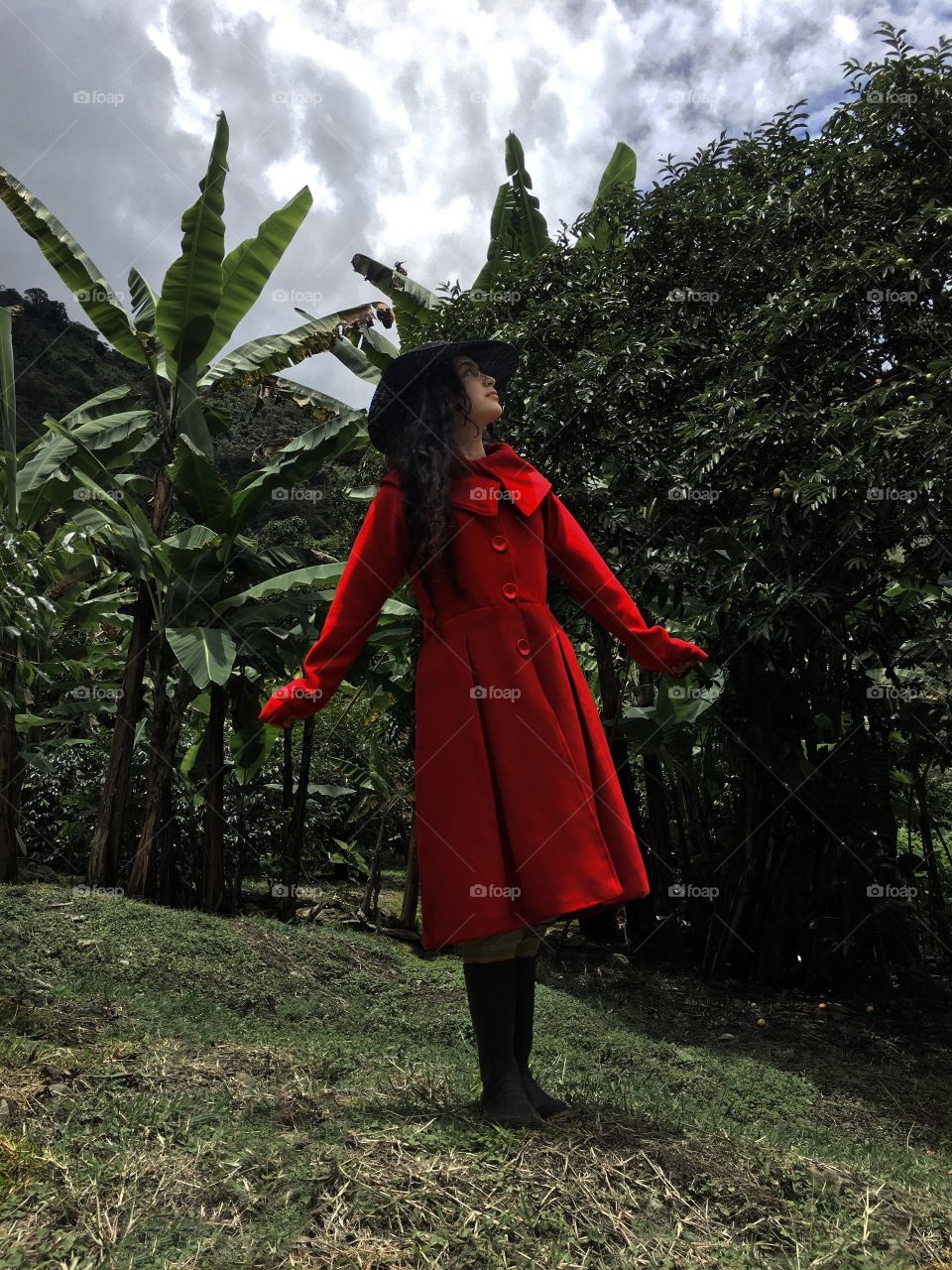 Joven con un vestido rojo en medio del campo, en una tarde oscura.