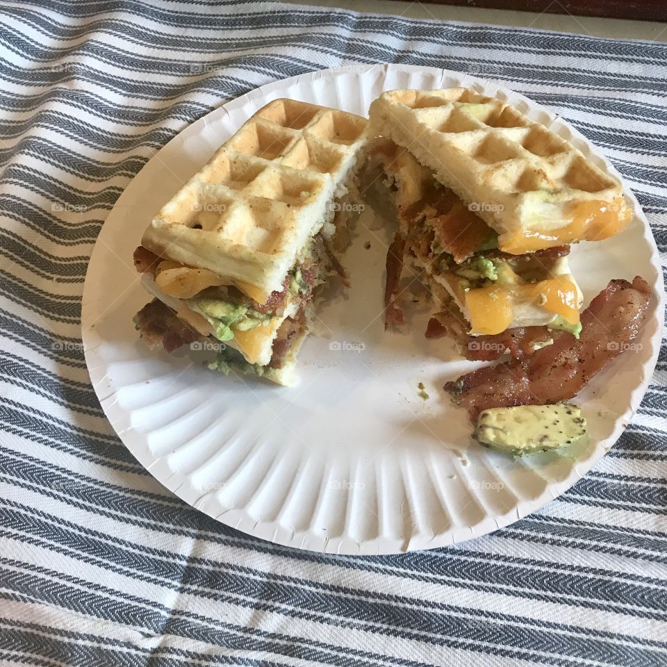 Your favorite sandwich. A waffle, avocado, bacon and cheese sandwich displayed on a white plate for lunch. USA, America 