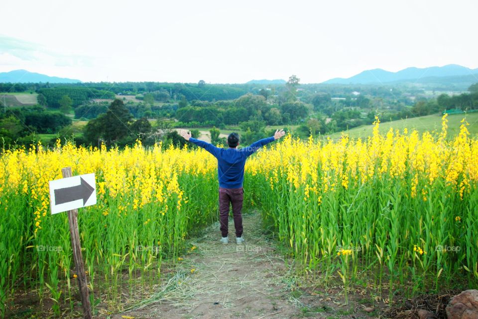 Men are happily standing among the blooming flowers and beautiful nature.