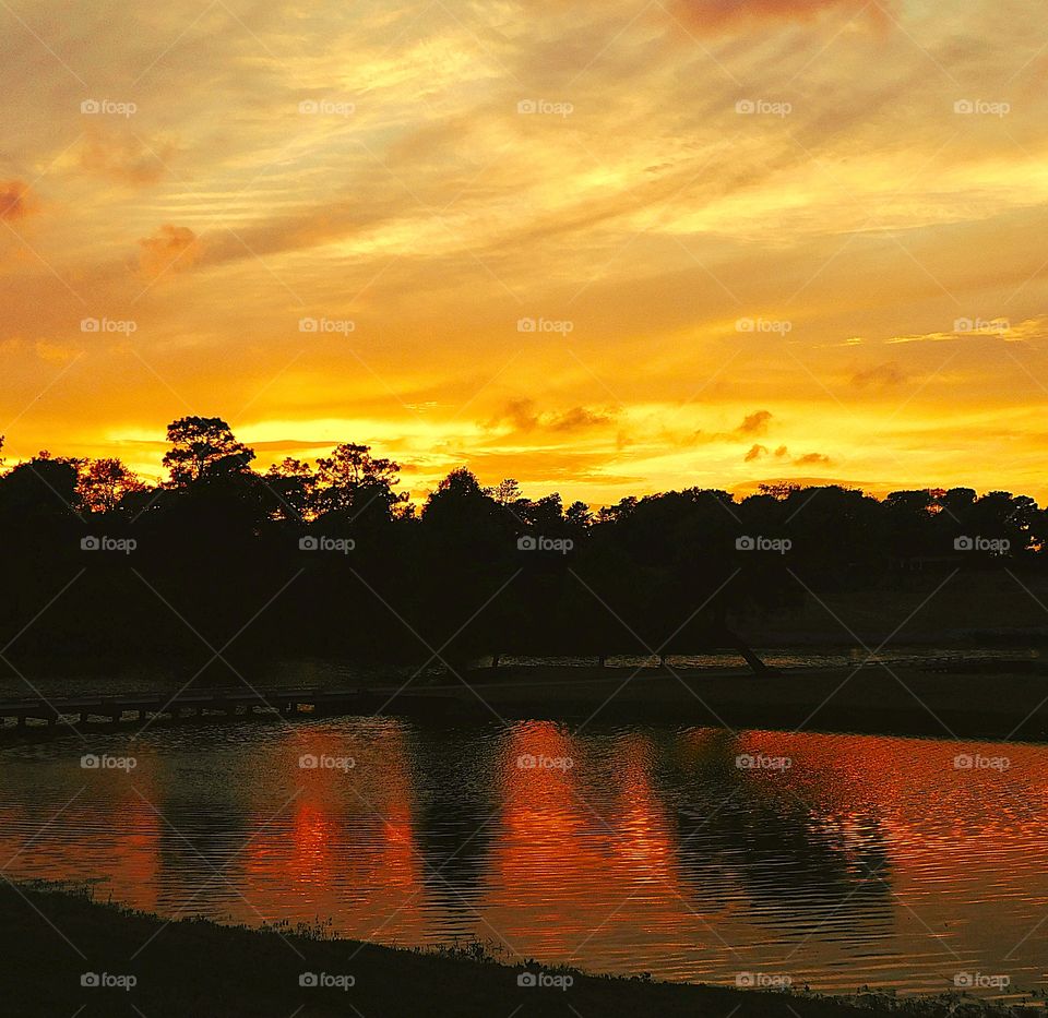 A spectacular sunset reflects from the trees and the radiant clouds