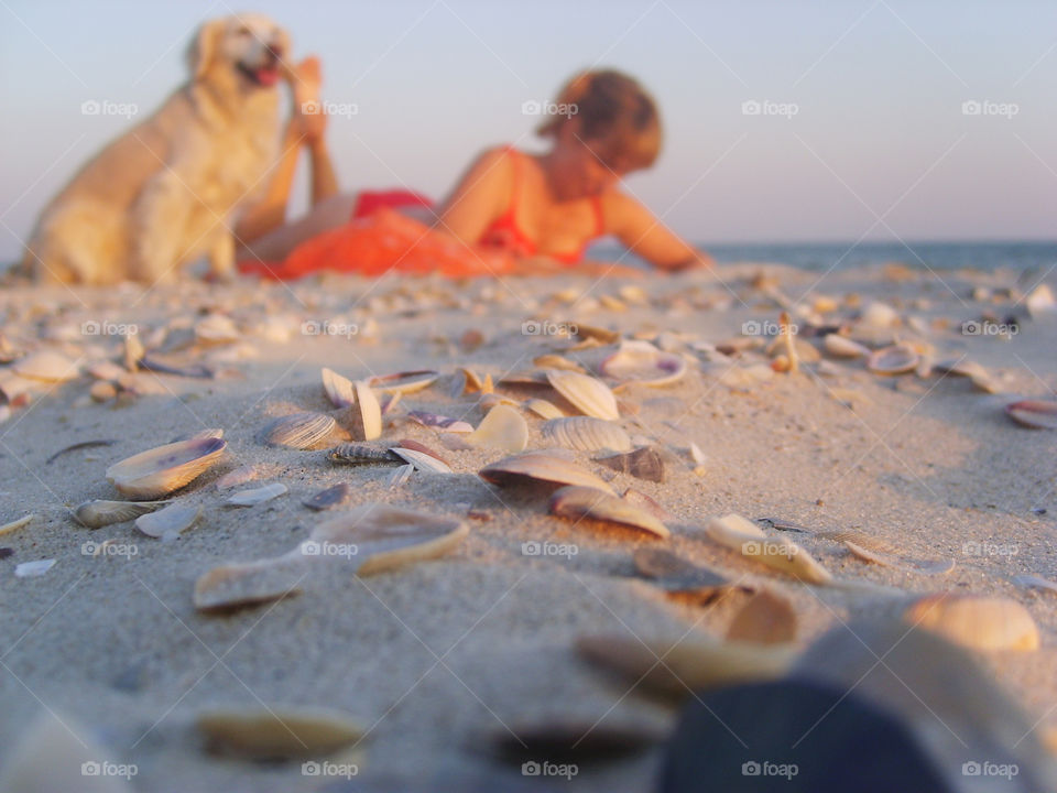 girl in a red bathing suit with a white dog lying on the beach