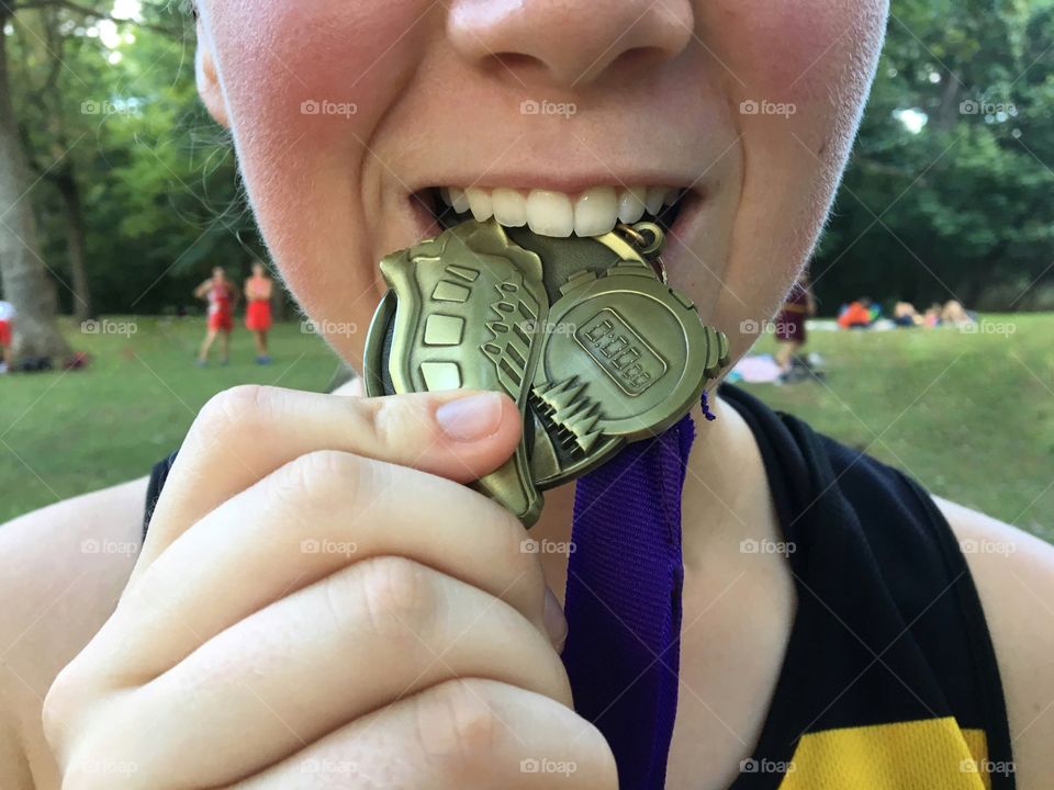Runner biting onto a medal. 