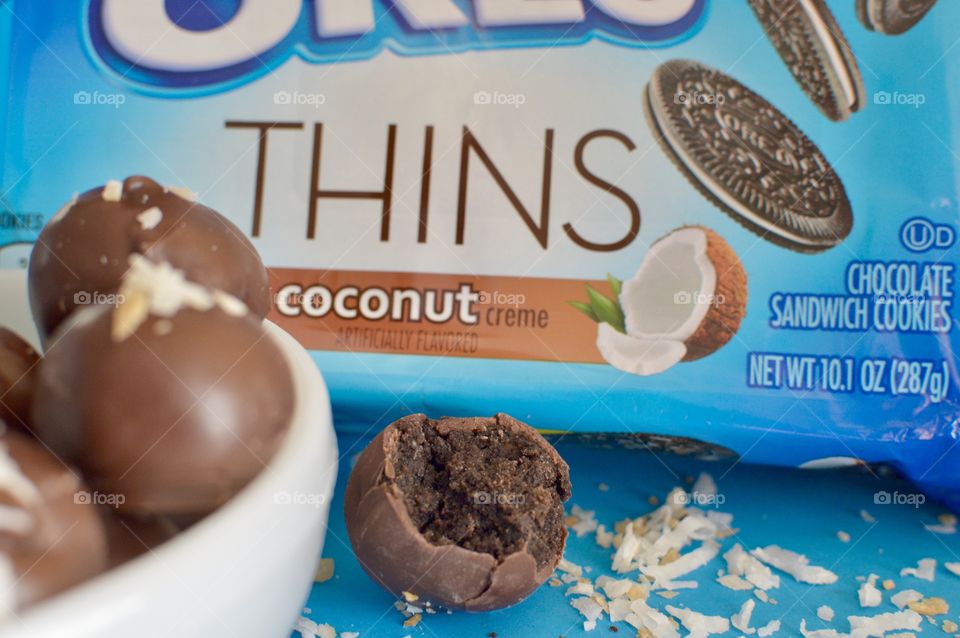 coconut Oreo thin cookies on a blue background with coconut shreds with truffles in a white bowl 