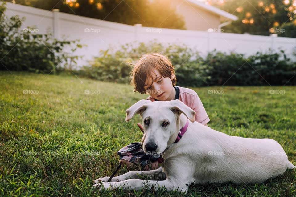 Little boy sitting on the grass with his dog