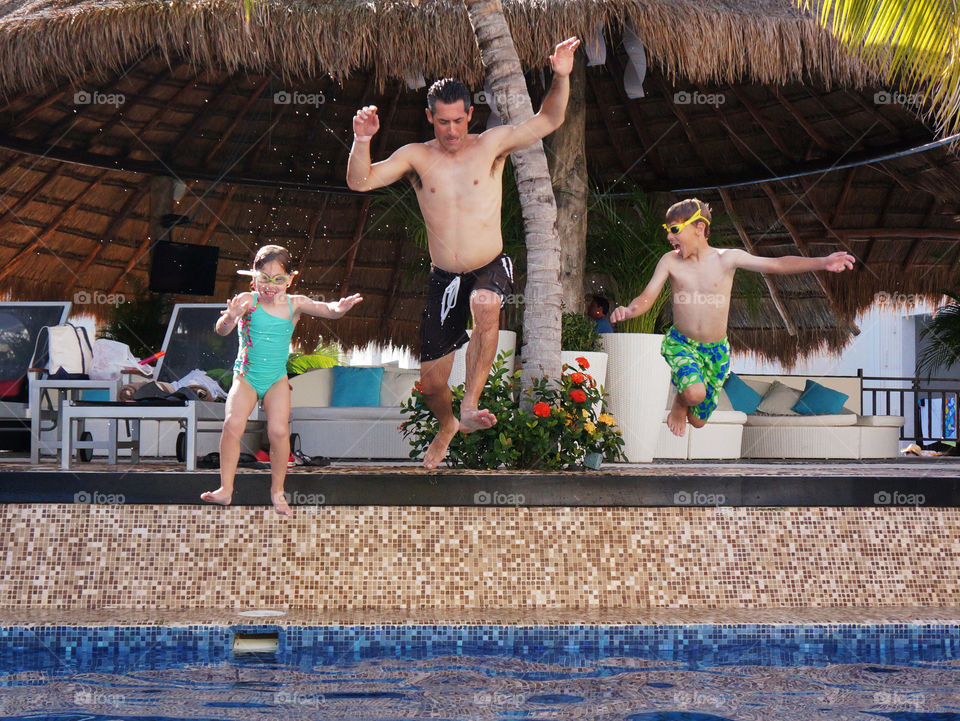 Happy family having fun together in outdoors swimming pool