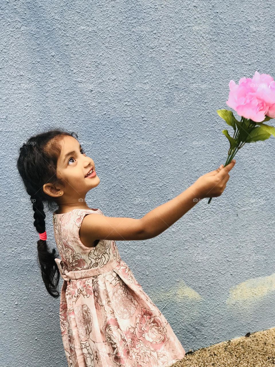 Beautiful girl’s long and black hair and she holds pink flowers in her hand 