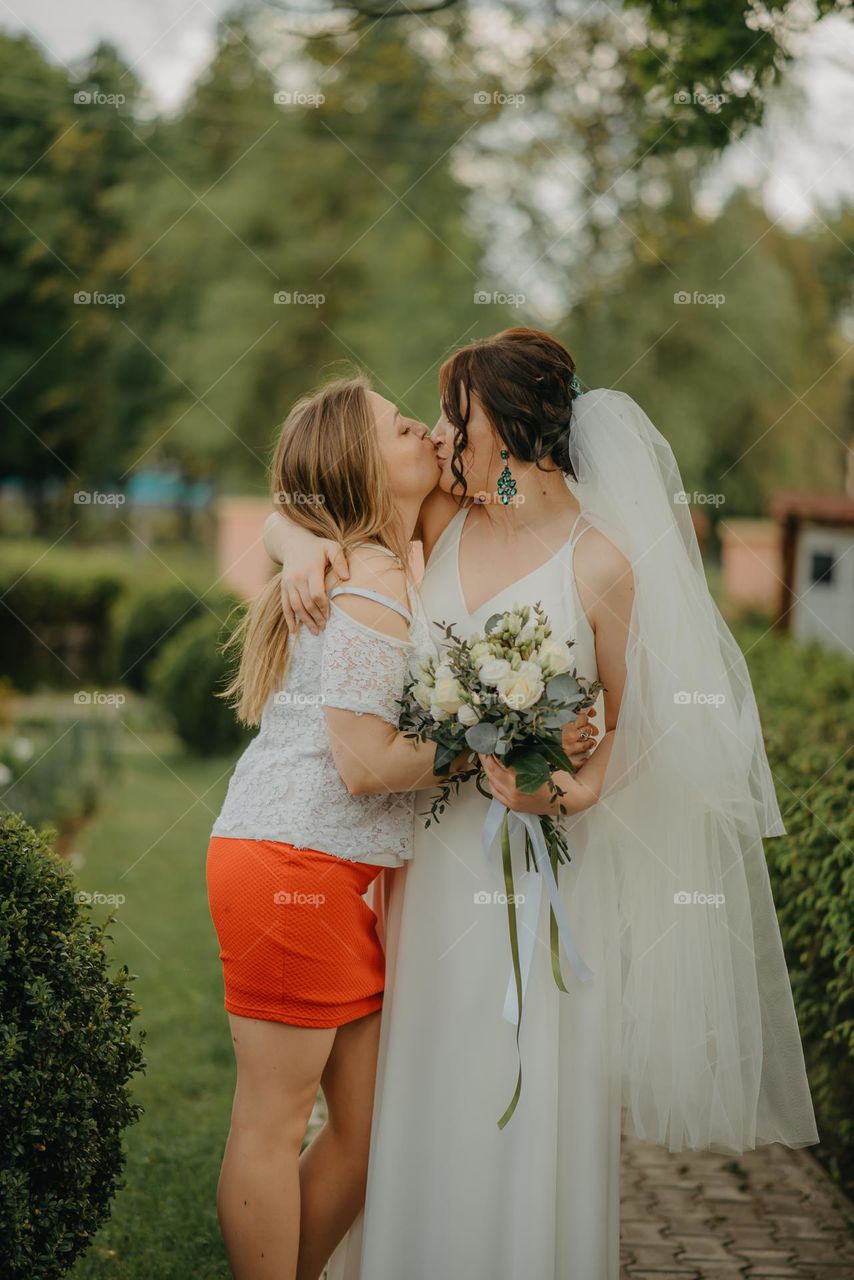 a warm kiss between two friends during a wedding procession