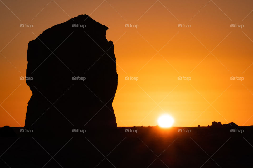 Silhouette photo of beautiful shape stone in front of beautiful Sunrise background at White desert in Egypt