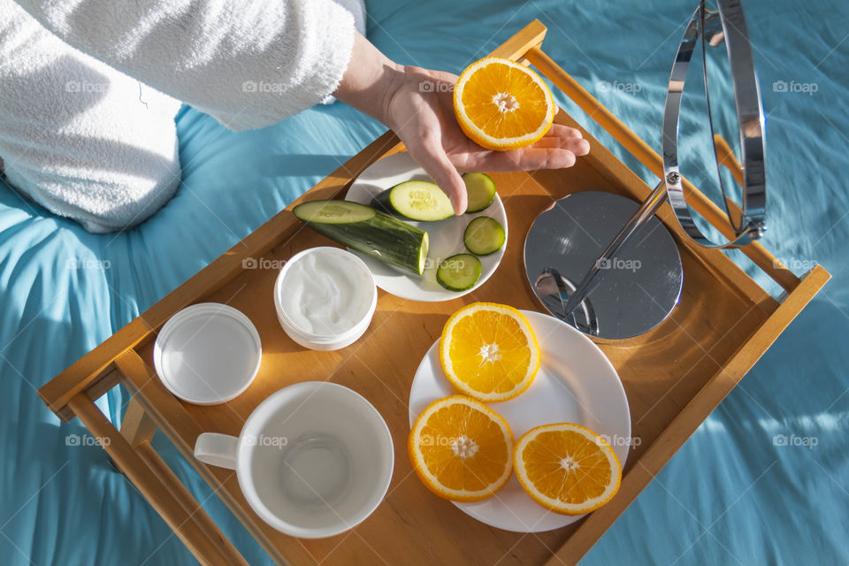 A man at home takes care of himself and does a manicure at home on a blue background and with orange.