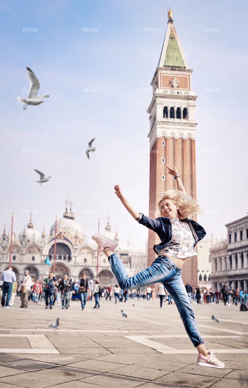 Happy girl jumping on a square in Venice