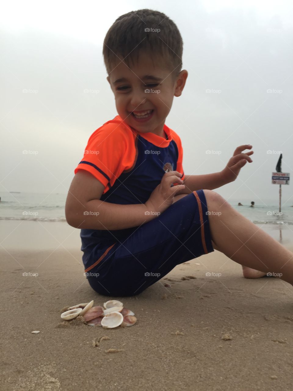 My son enjoying play with seashell on the beach