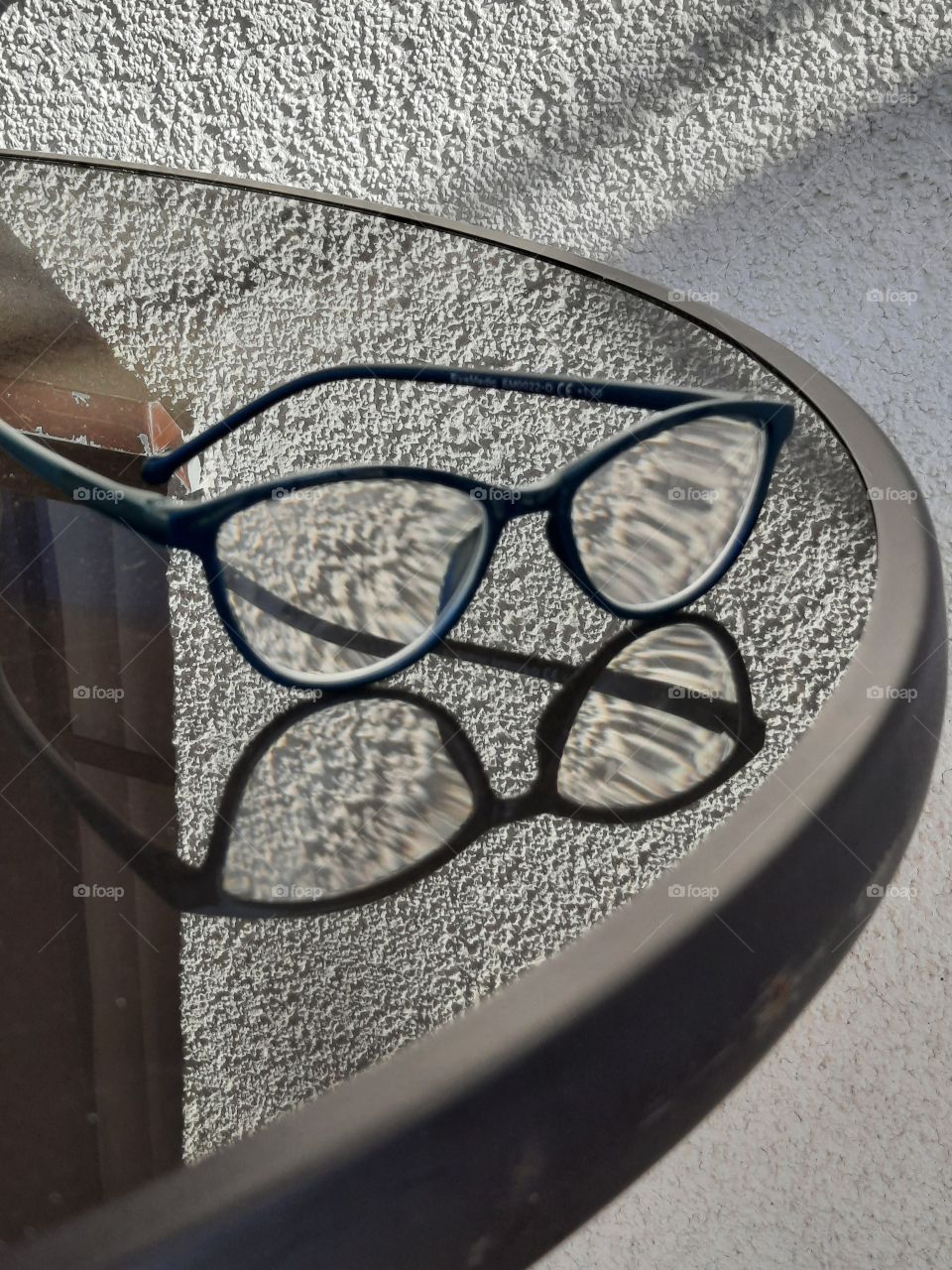 pair spectacles reflecting in glass table