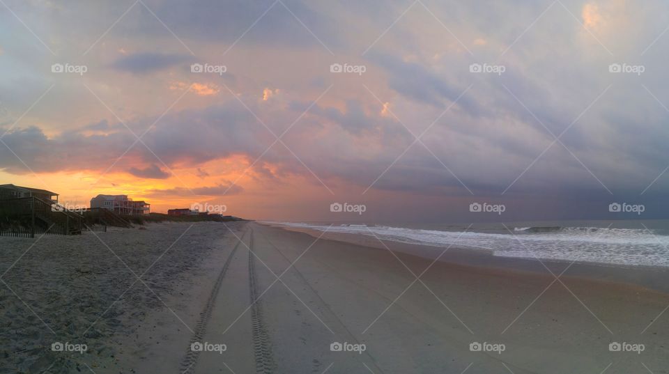 View of beach against cloudy sky at sunrise