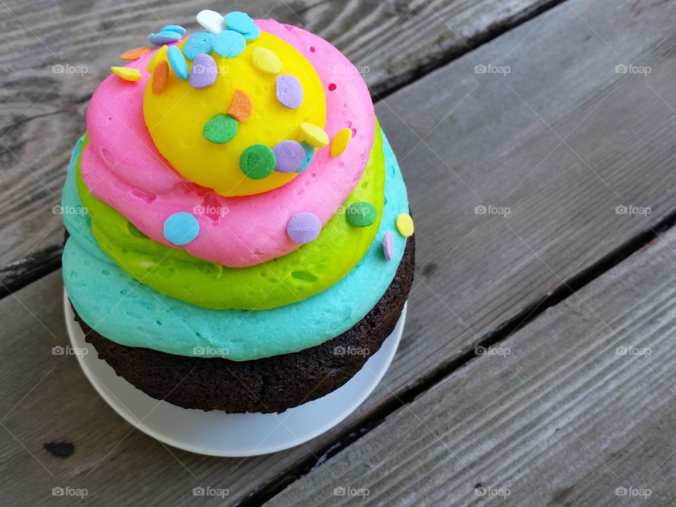 Celebration cupcake on wooden table, left 2. (Lower angle)