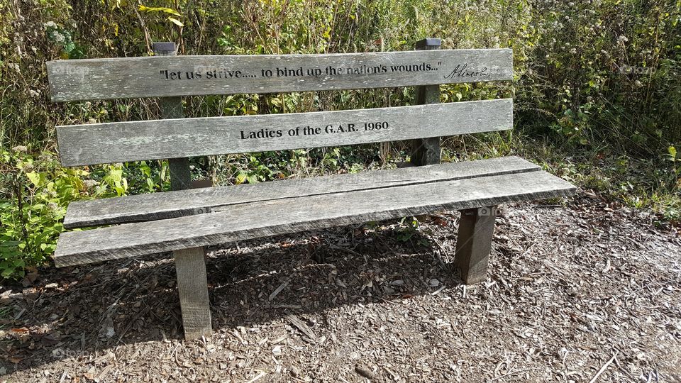 an aging bench with a fading inscription of one of Lincoln's famous quotes, at the Abraham Lincoln Memorial Gardens